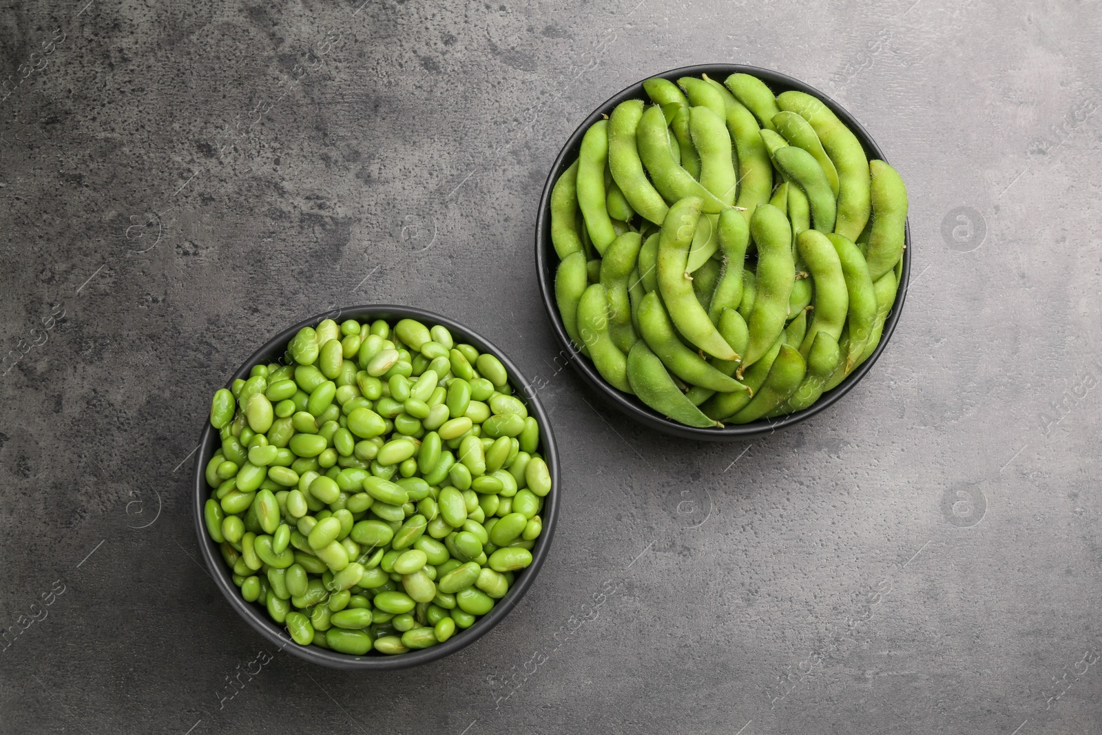 Photo of Raw green edamame soybeans and pods on grey table, top view