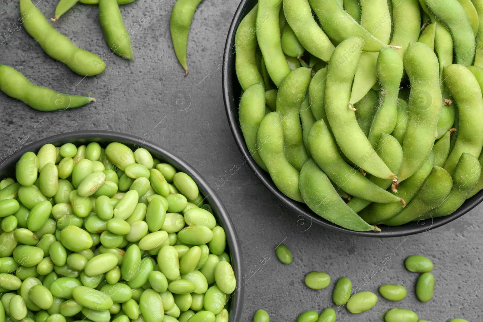 Photo of Raw green edamame soybeans and pods on grey table, top view