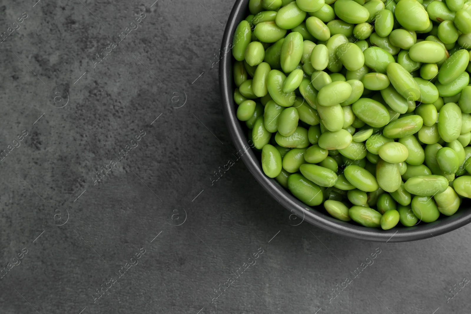 Photo of Raw green edamame soybeans on grey table, top view. Space for text