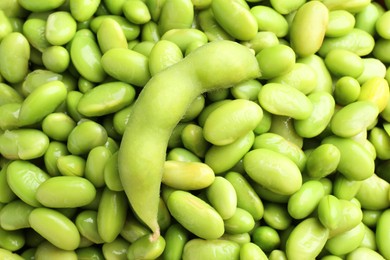 Photo of Raw green edamame pod on soybeans as background, closeup