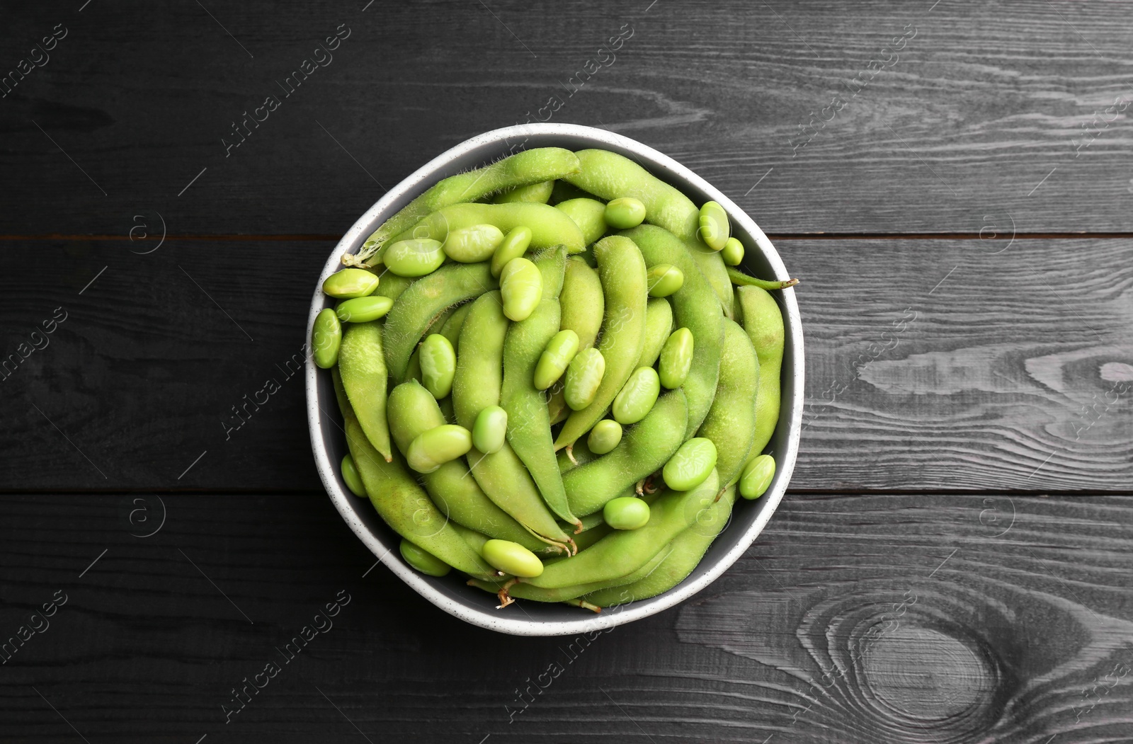 Photo of Raw green edamame soybeans and pods on wooden table, top view