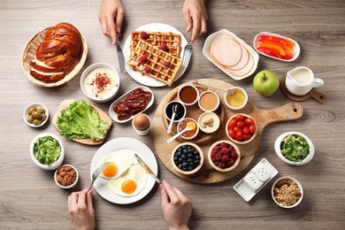 People having breakfast at wooden table, top view