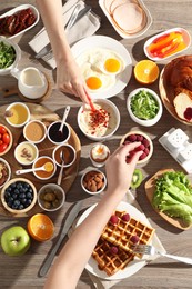 Photo of People having breakfast at wooden table, top view