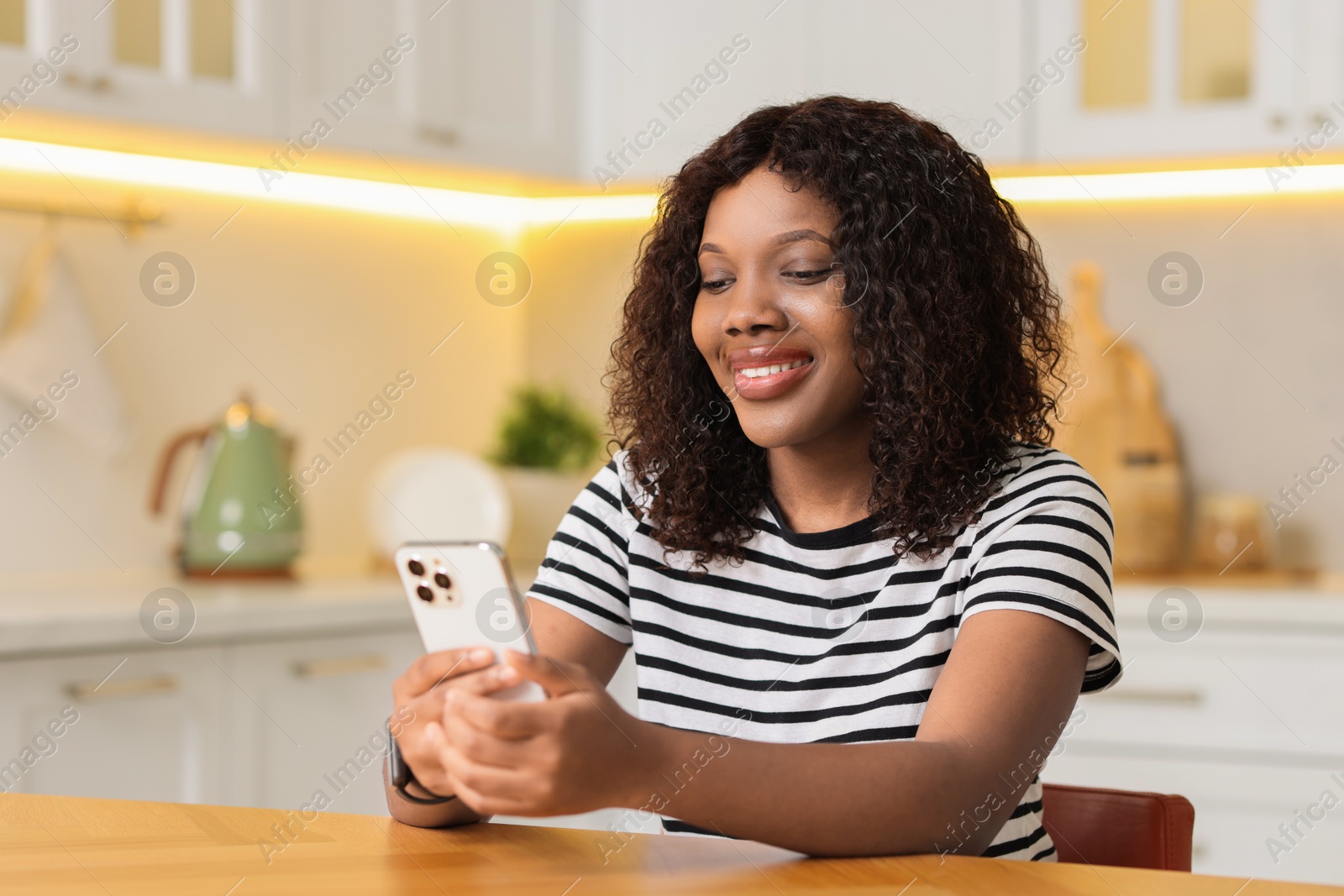 Photo of Beautiful woman using mobile phone at table indoors