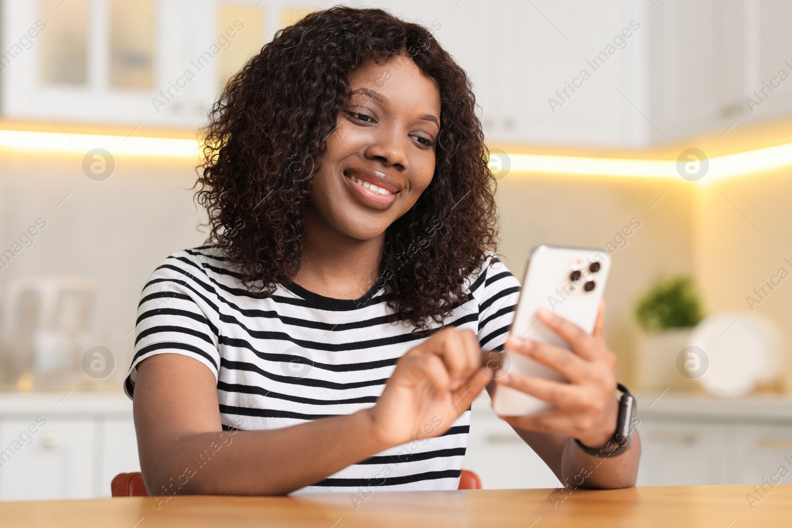 Photo of Beautiful woman using mobile phone at table indoors