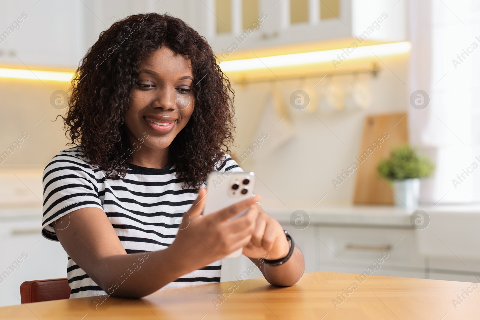 Photo of Beautiful woman using mobile phone at table indoors