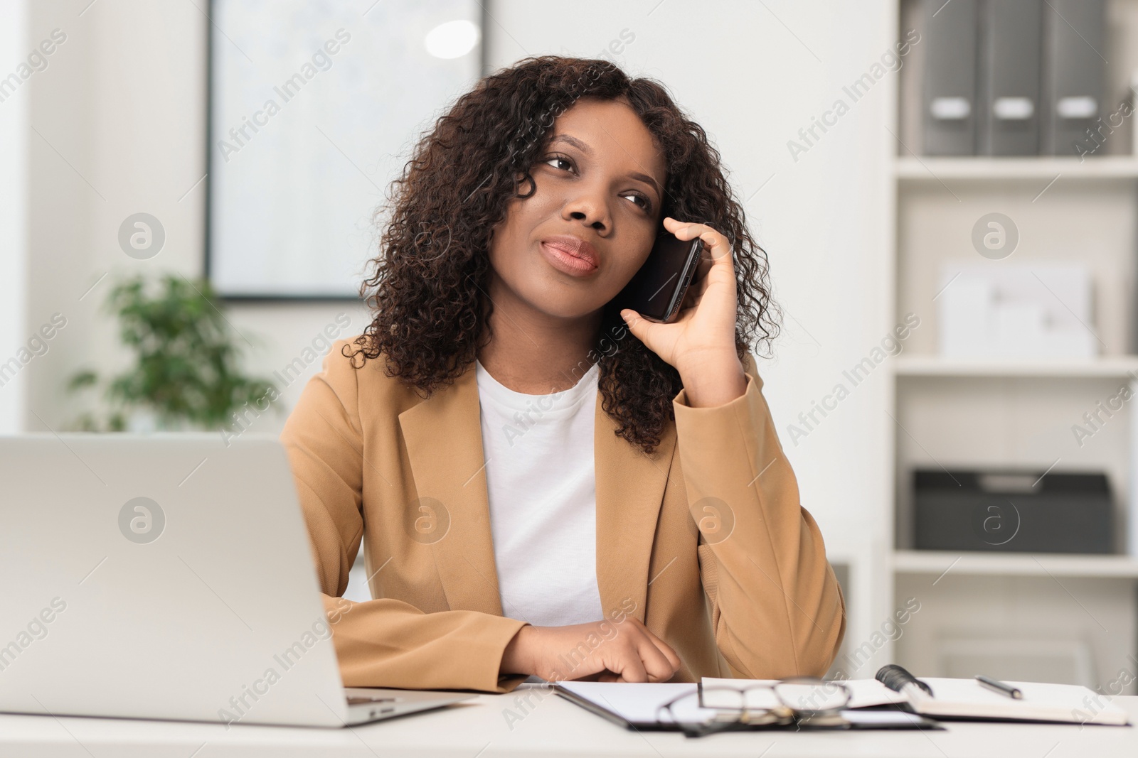 Photo of Beautiful woman talking on mobile phone in office