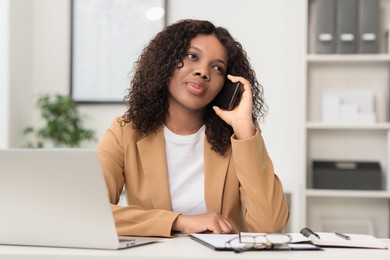 Beautiful woman talking on mobile phone in office