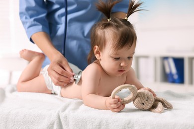 Pediatrician examining cute little girl with stethoscope in clinic, closeup. Checking baby's health