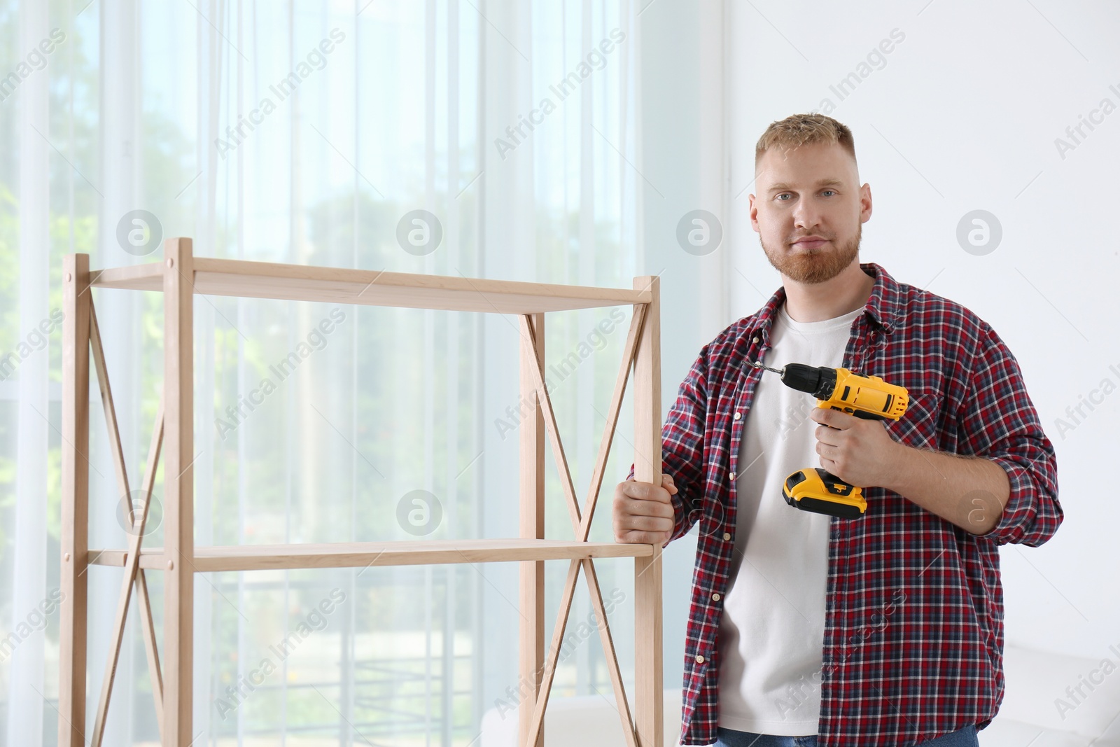 Photo of Man with electric screwdriver at home. Assembling furniture