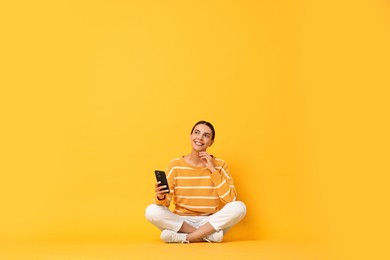 Photo of Happy woman with smartphone on yellow background