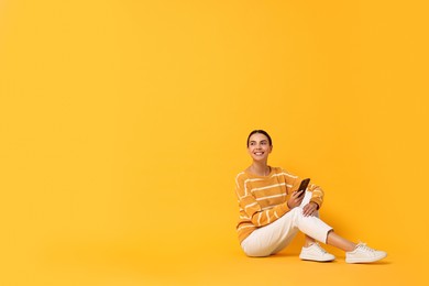 Photo of Happy woman with smartphone on yellow background. Space for text