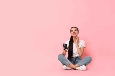 Photo of Smiling woman with smartphone on pink background. Space for text