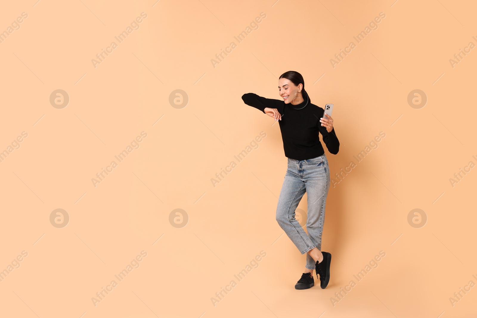 Photo of Smiling woman with smartphone on beige background. Space for text