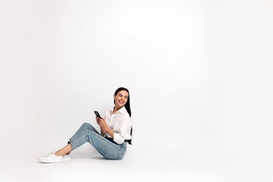 Smiling woman with smartphone on white background. Space for text