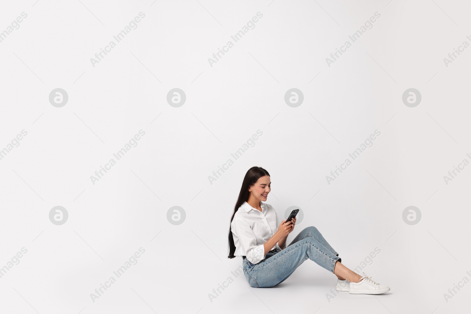 Photo of Smiling woman with smartphone on white background. Space for text