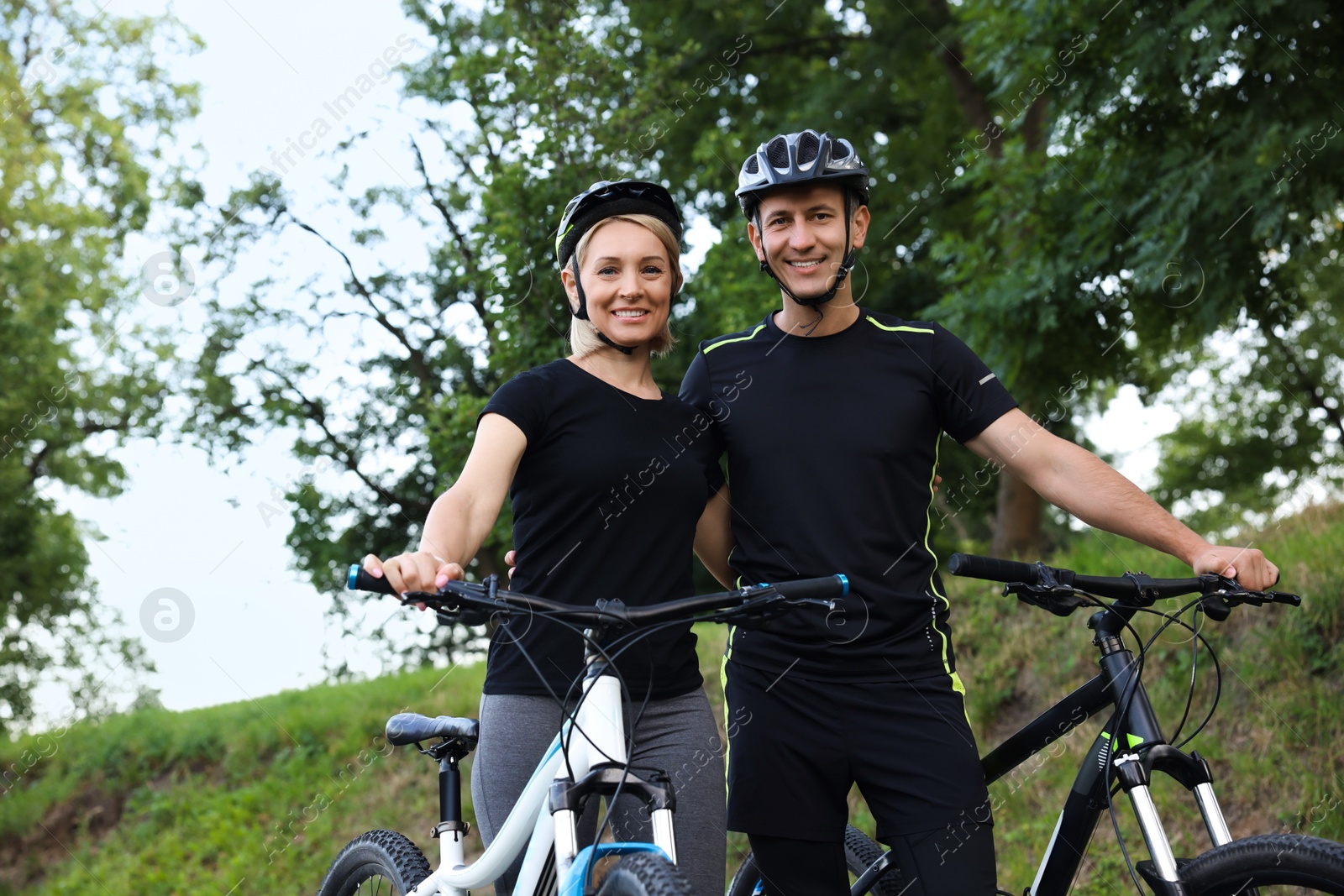 Photo of Happy couple with bicycles in park, low angle view