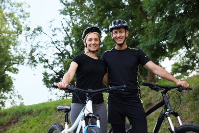 Photo of Happy couple with bicycles in park, low angle view