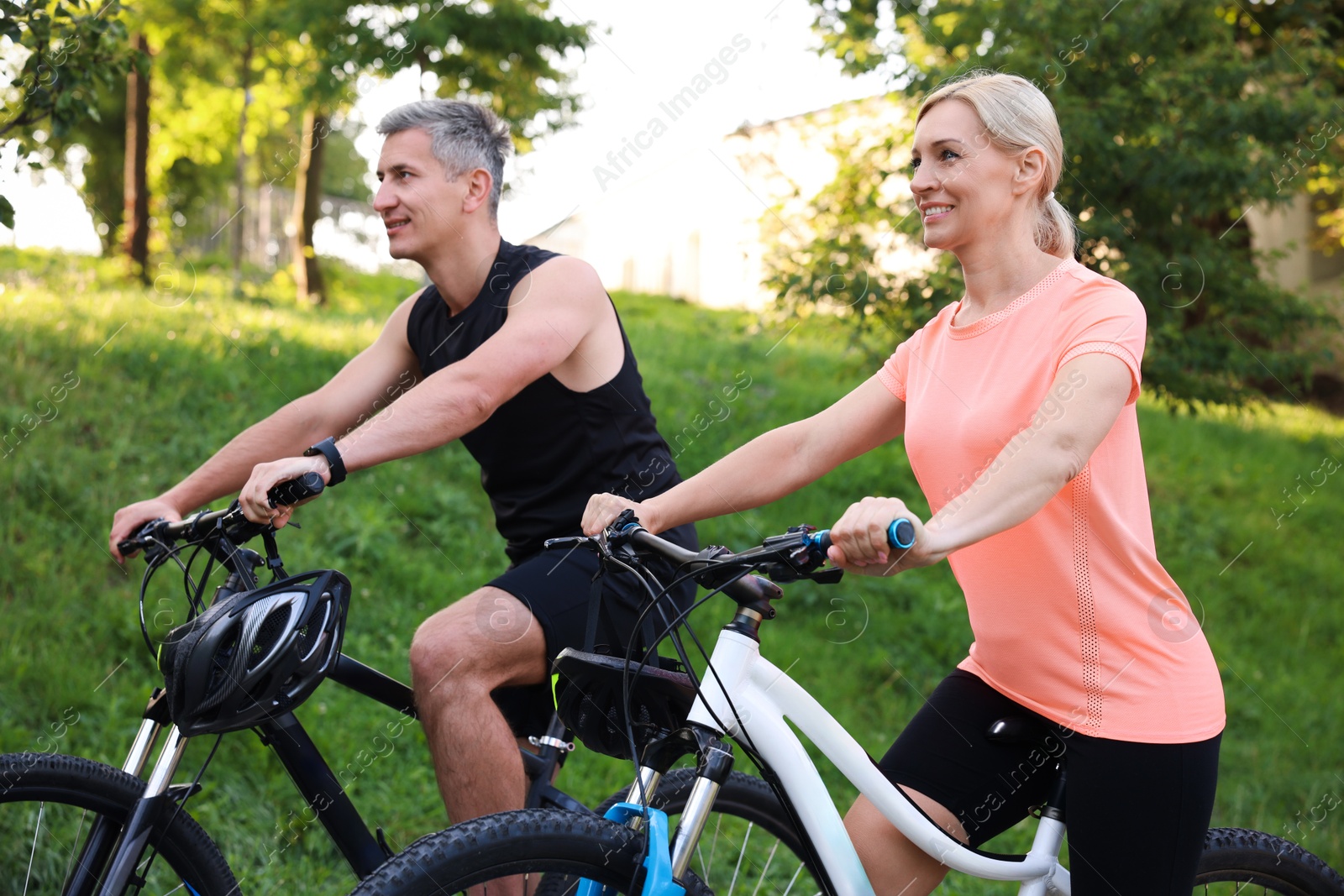 Photo of Happy couple riding bicycles in park. Healthy lifestyle