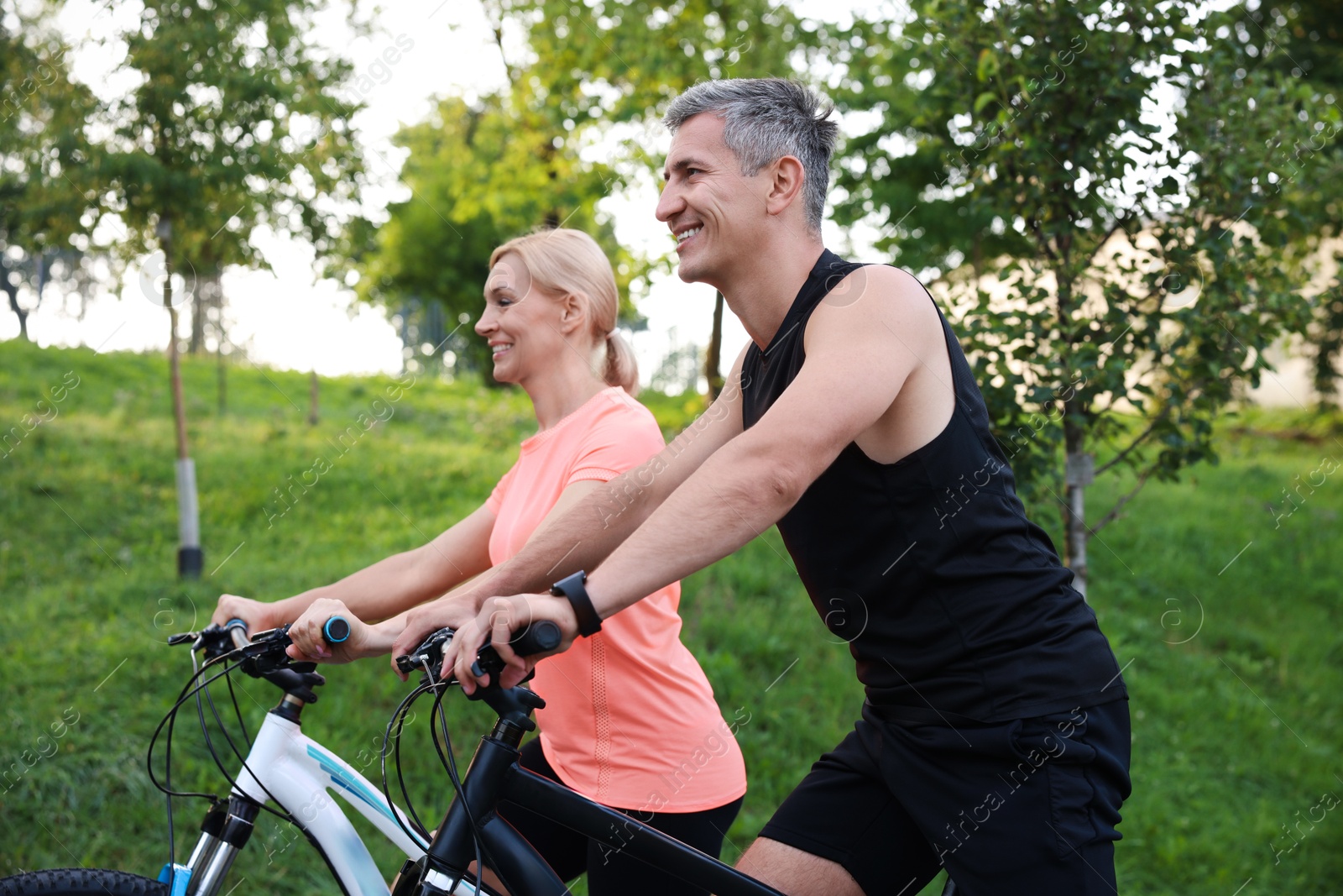 Photo of Happy couple riding bicycles in park. Healthy lifestyle