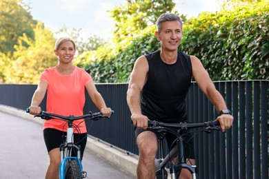 Happy couple riding bicycles outdoors, selective focus