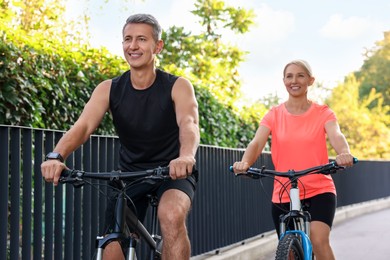 Happy couple riding bicycles outdoors, selective focus