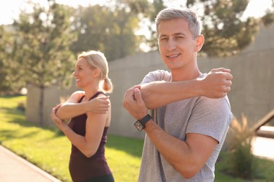 Photo of Happy couple doing exercises in park, selective focus