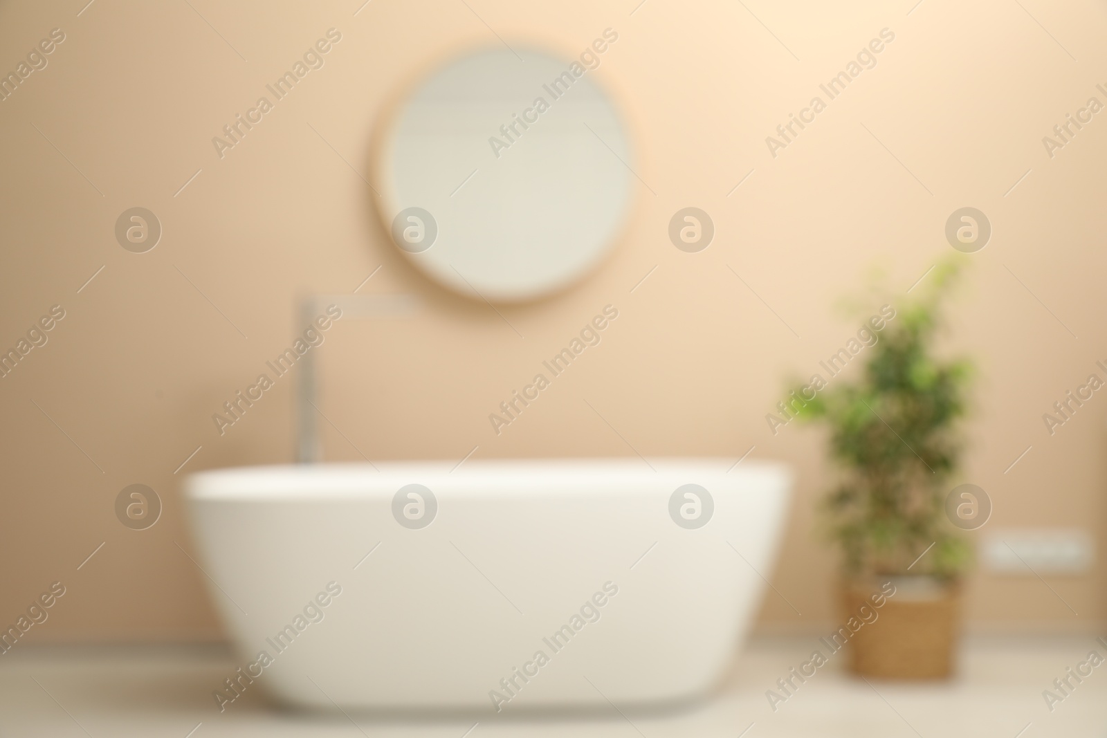 Photo of Blurred view of bathtub, houseplant and mirror in stylish bathroom