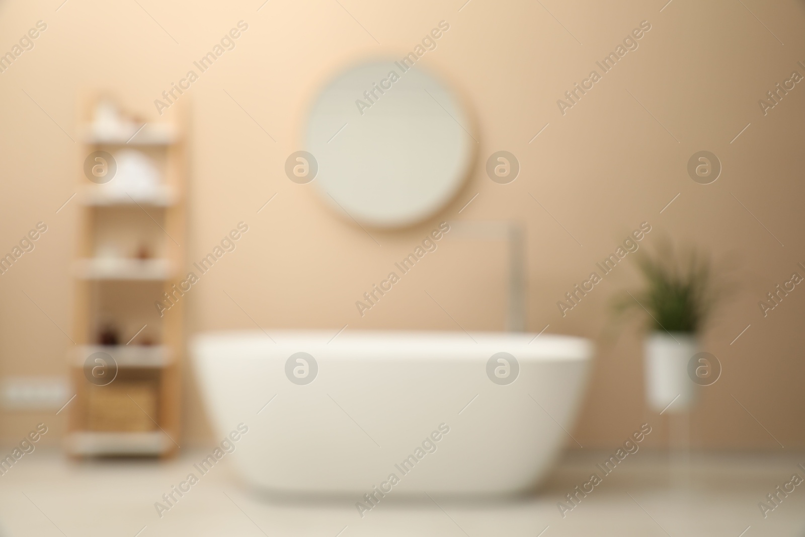 Photo of Blurred view of bathtub, houseplant, shelving unit and mirror in stylish bathroom