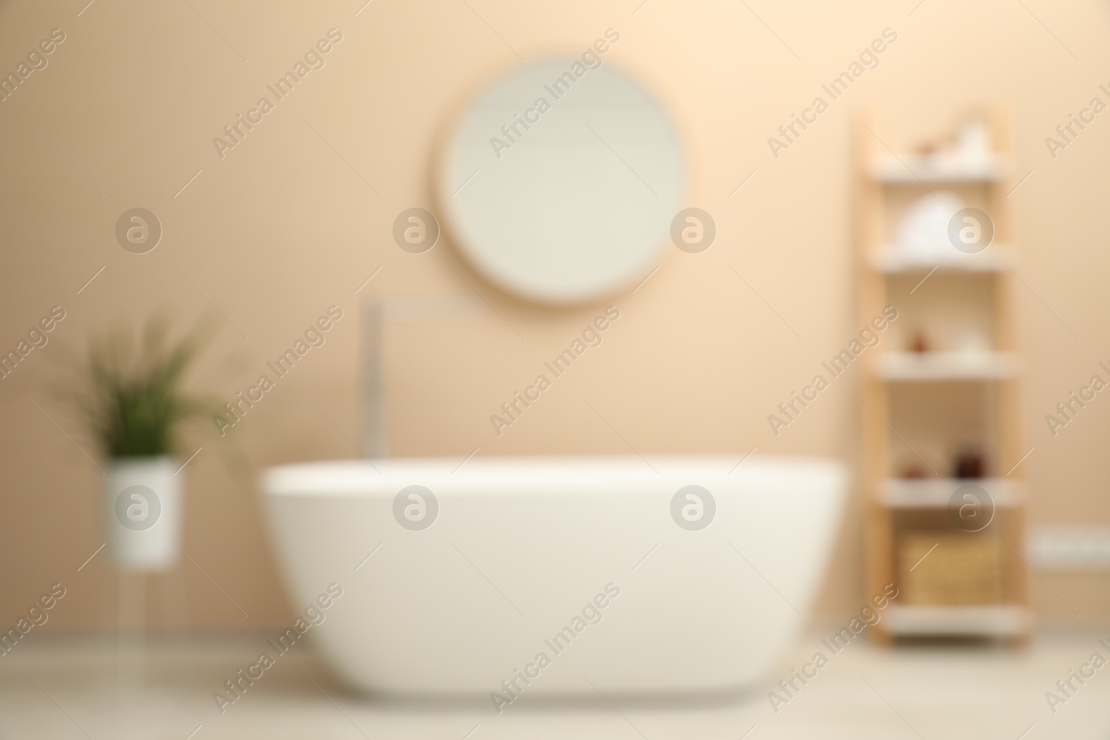 Photo of Blurred view of bathtub, houseplant, shelving unit and mirror in stylish bathroom