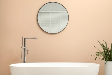 Photo of Bathtub, houseplant and mirror in stylish bathroom