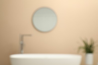 Photo of Blurred view of bathtub, houseplant and mirror in bathroom