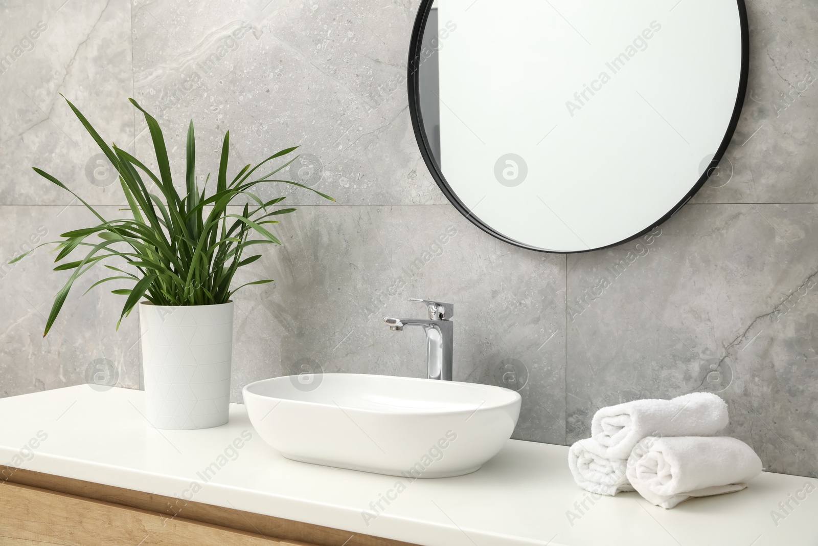 Photo of Countertop with sink, towels, houseplant and mirror in bathroom