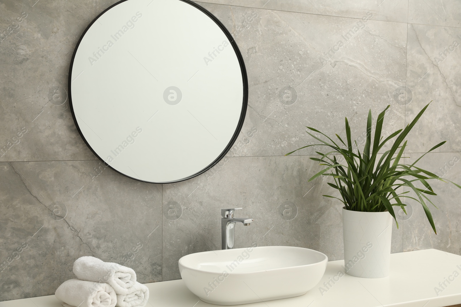 Photo of Countertop with sink, towels, houseplant and mirror in bathroom