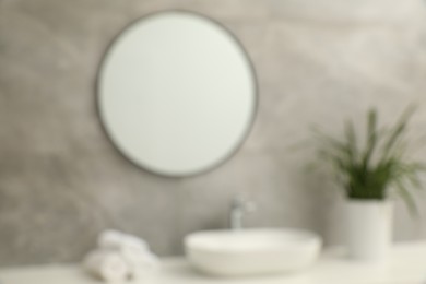 Photo of Blurred view of countertop with sink, towels, houseplant and mirror in bathroom