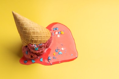 Photo of Melted ice cream in wafer cone on yellow background. Space for text