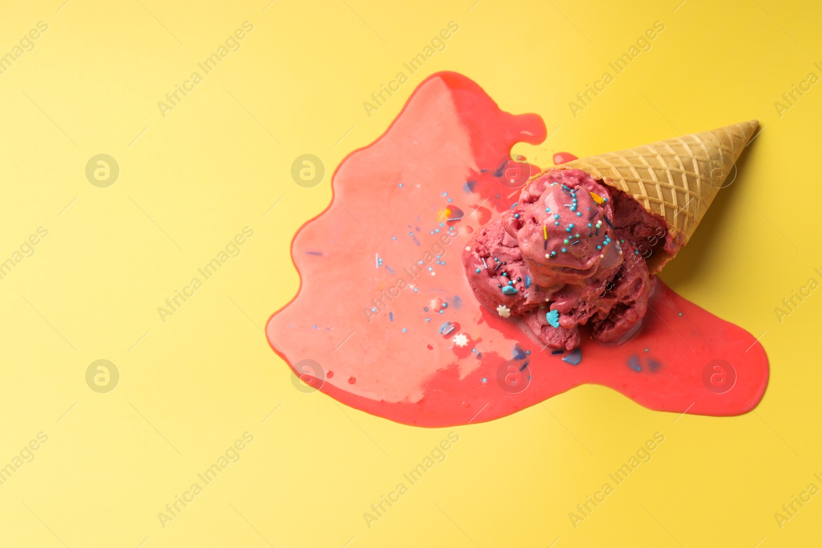 Photo of Melted ice cream in wafer cone on yellow background