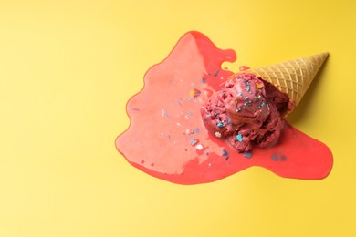 Photo of Melted ice cream in wafer cone on yellow background