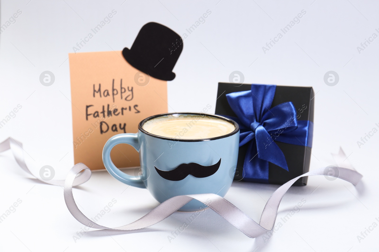 Photo of Greeting card with phrase Happy Father's Day, gift and cup of coffee on light background