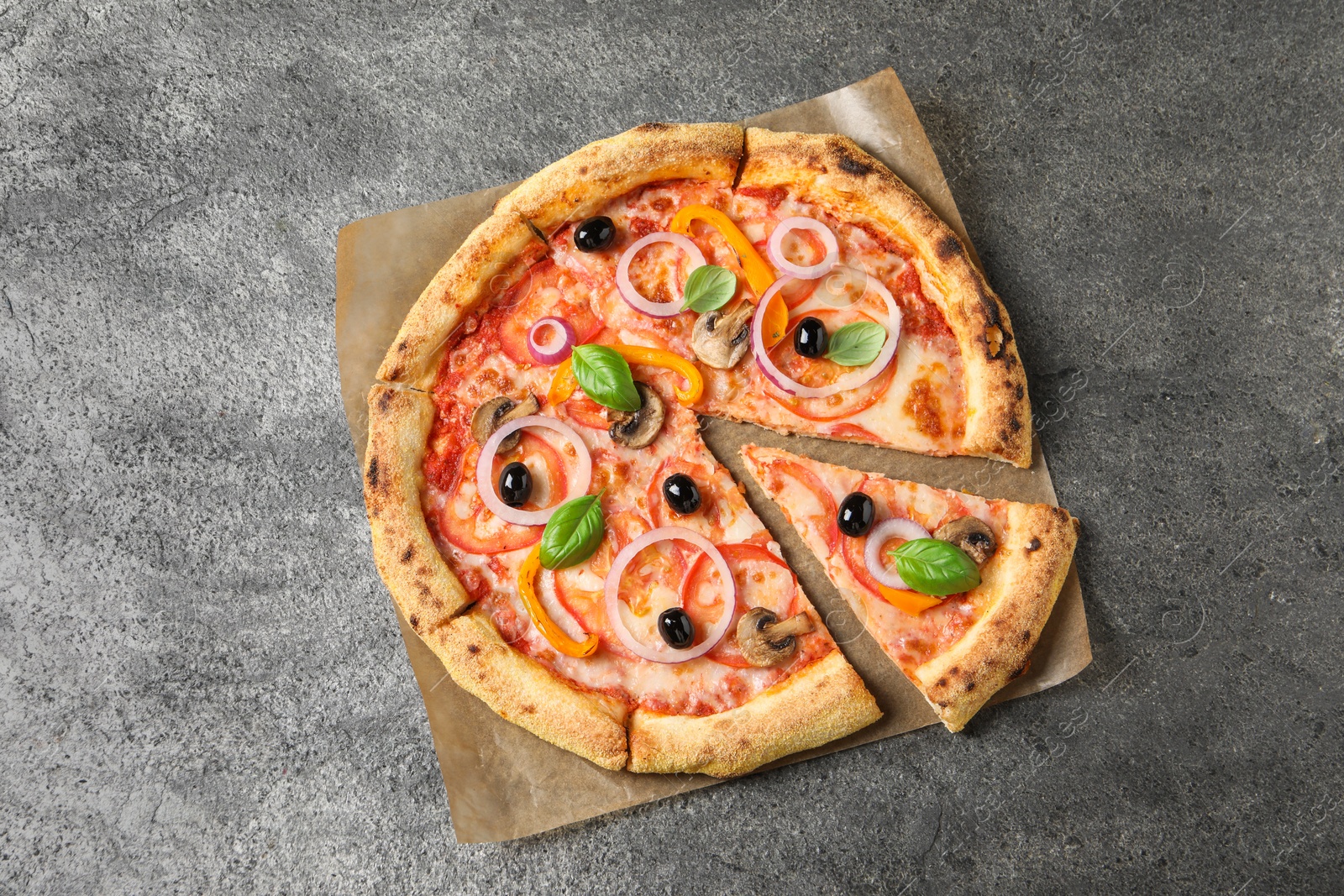 Photo of Cut delicious vegetarian pizza on grey table, top view