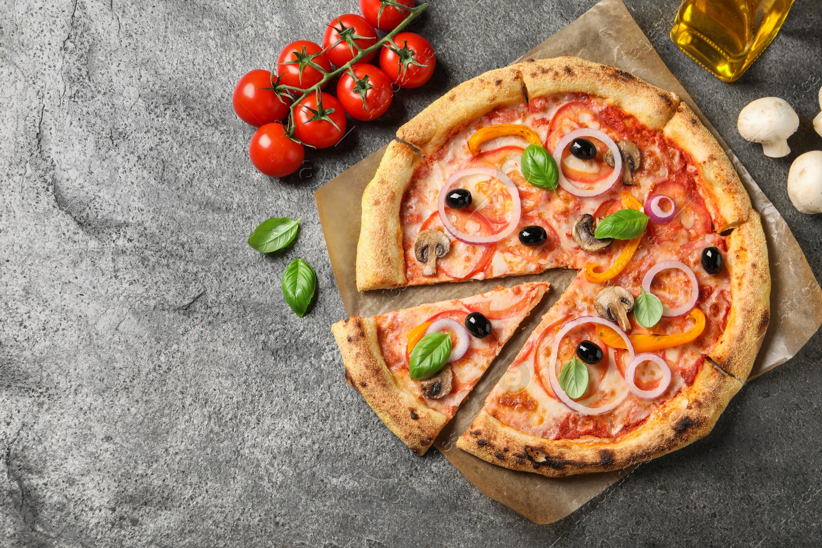 Photo of Cut delicious vegetarian pizza and ingredients on grey table, flat lay. Space for text