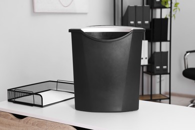 Paper shredder with bin on white table in office