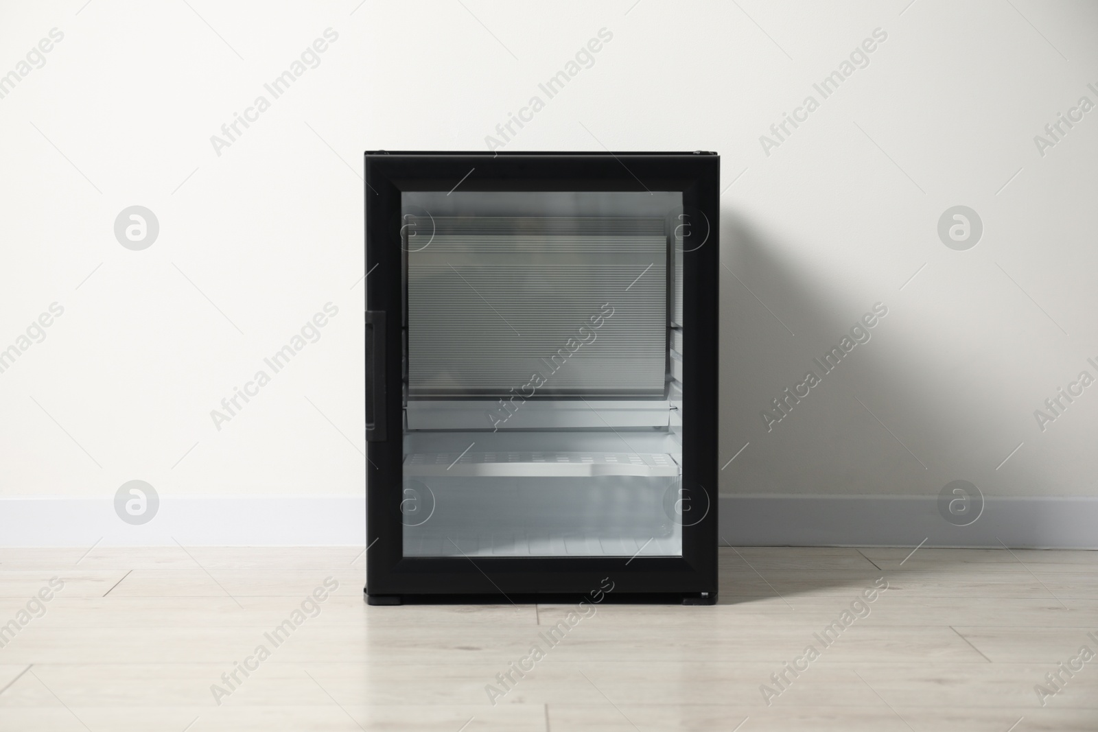 Photo of Empty modern mini refrigerator near white wall