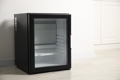 Photo of Empty modern mini refrigerator near white wall