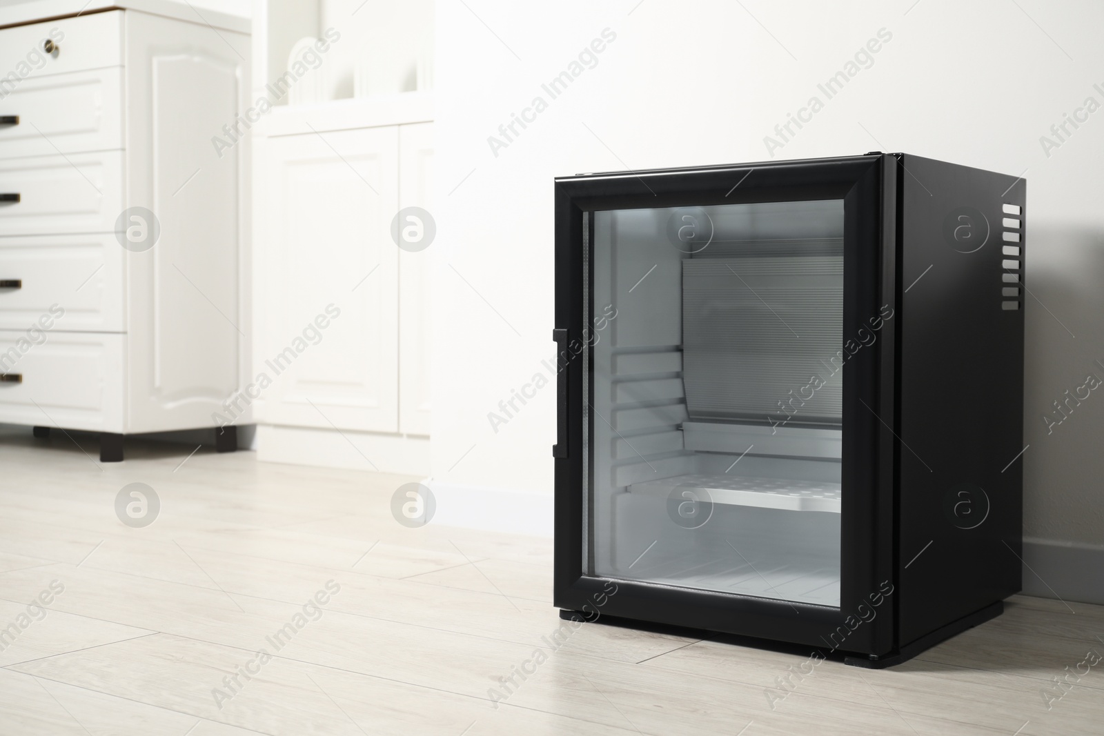 Photo of Empty modern mini refrigerator near white wall, space for text