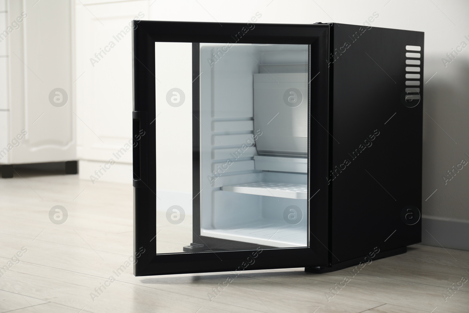 Photo of Empty modern mini refrigerator near white wall