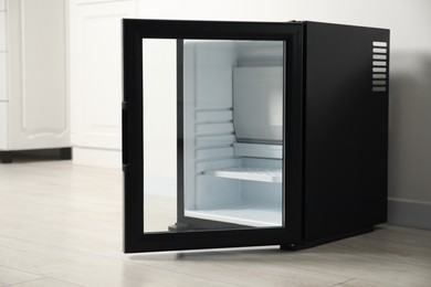 Photo of Empty modern mini refrigerator near white wall