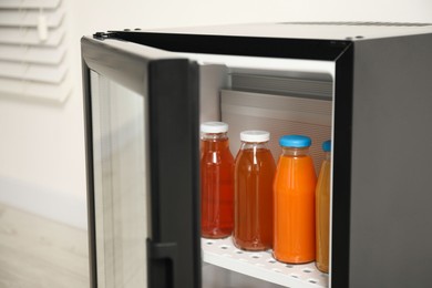 Photo of Open mini refrigerator with different drinks indoors