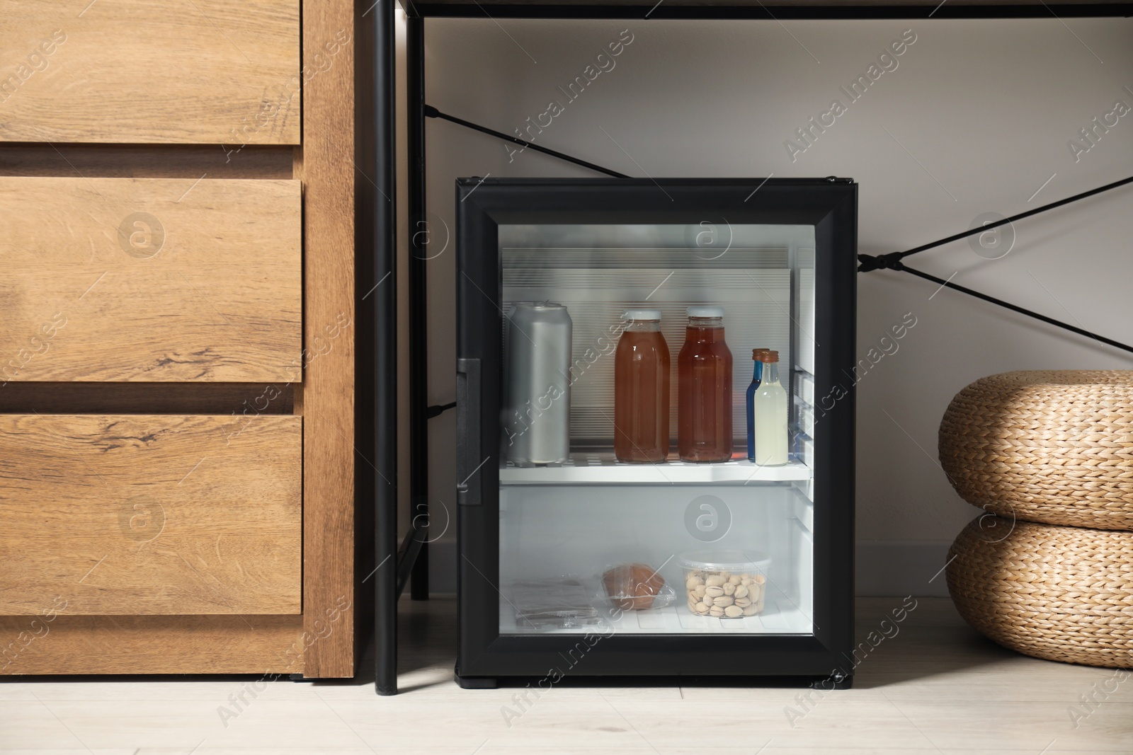 Photo of Mini refrigerator with different drinks and snacks indoors