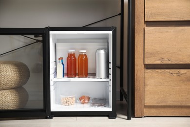 Mini refrigerator with different drinks and snacks indoors